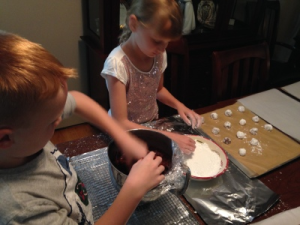 Rolling the cookies in icing sugar while using teamwork